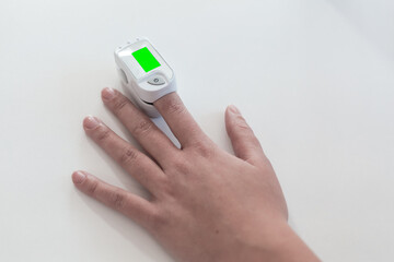 Pulse oximeter on a woman's finger. blood oxygen saturation. The patient measures the saturation of the blood with an electronic pulse oximeter on the finger - 484522491