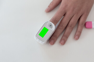 Pulse oximeter on a woman's finger. blood oxygen saturation. The patient measures the saturation of the blood with an electronic pulse oximeter on the finger - 484522627