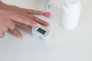 Pulse oximeter on a woman's finger. blood oxygen saturation. The patient measures the saturation of the blood with an electronic pulse oximeter on the finger - 484522699