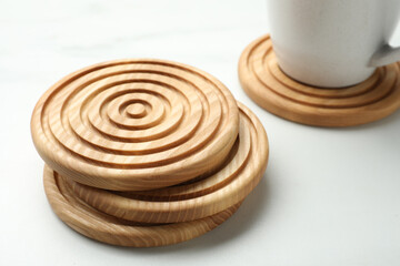 Stylish wooden cup coasters on white marble table