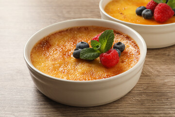 Delicious creme brulee with fresh berries on wooden table