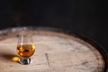 Glencairn glass with whiskey on bourbon barrel
