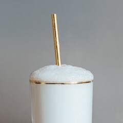 Ramos gin fizz in gold rim glass with gold straw 