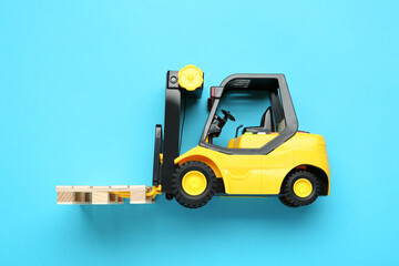 Toy forklift with wooden pallet on light blue background, top view