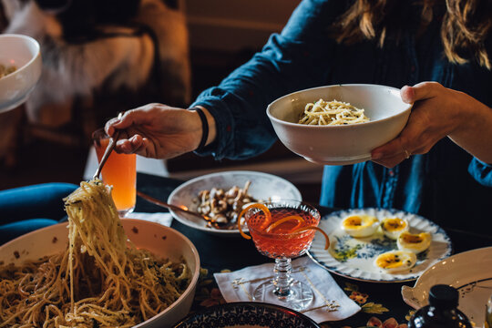 woman serving herself spaghetti noodles over table full of food