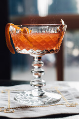 blood orange sparkling cocktail in vintage crystal coupe glass with orange twist garnish