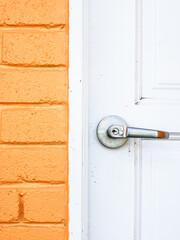 Image of dirty white wooden door with knob and yellow bricks wall.
