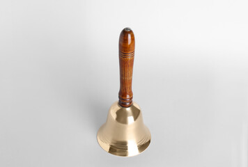 Golden school bell with wooden handle on grey background