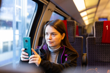 Fototapeta na wymiar Caucasian woman photographing with her smartphone while traveling by train.
