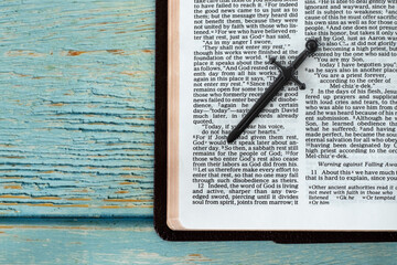 Open Holy Bible Book with a sword on blue wooden background with copy space. The biblical concept...