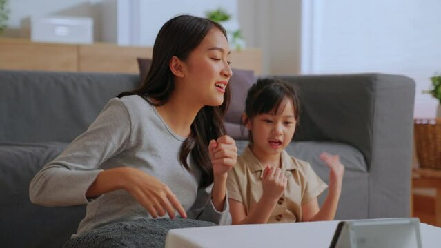 Active mom babysiter and cute little daughter Watch online music videos on your mobile phone and dancing in living room at home. Happy family mother and children enjoy activities together at holiday.