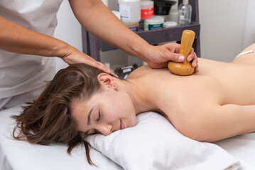 Obraz na płótnie Canvas young woman in an aesthetic center undergoing a treatment for the beauty of the skin and body with the wood therapy method applied by an aesthetic professional