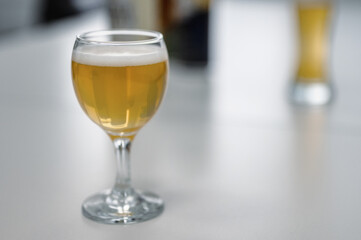 A glass filled with beer stands on a white table