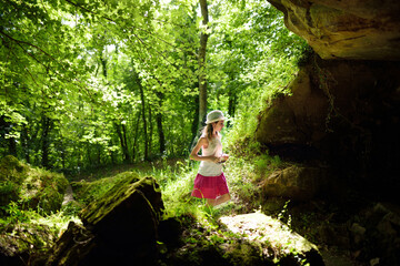 Young girl exploring old caves dug into the tuff rock and used for human habitation in ancient...