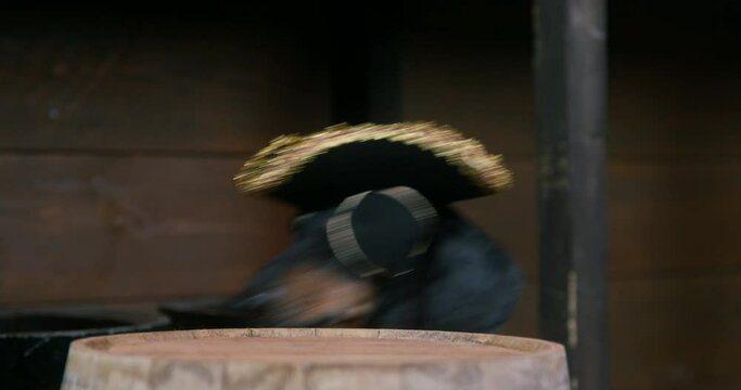 Black dachshund friend dressed as pirate with eyepatch and cocked hat looks at wooden barrel with rum IN cabin of ship closeup