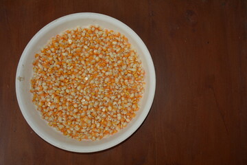 Orange corn kernels on a white tray, on a brown wooden texture background