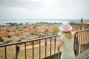Young girl exploring medieval streets of picturesque resort town Bolsena, situated on the shores of...