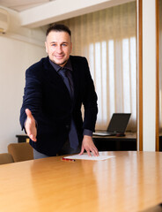 Smiling executive young adult man welcoming partners to meeting room