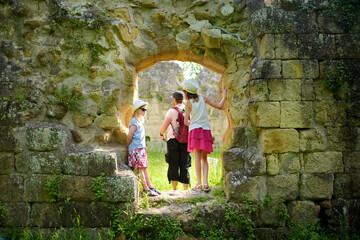 Fototapeta na wymiar Family of three exploring old caves dug into the tuff rock and used for human habitation in ancient times. Citta del Tufo archaeological park.