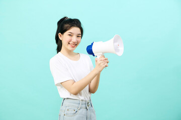 Asian woman holding megaphone on blue background