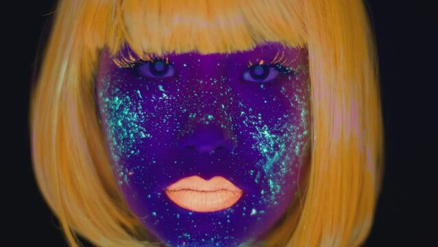Close up portrait of young asian lady with ultraviolet space makeup and orange wig and lips looking at camera
