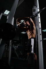 Muscular athletic young man fitness model resting after exercises in gym