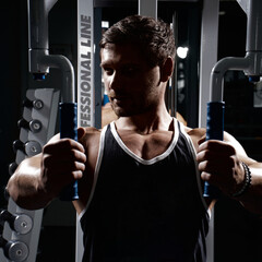 Muscular athletic young man fitness model do exercises in gym