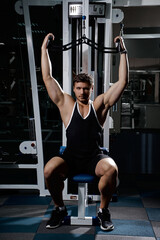 Muscular athletic young man fitness model do exercises in gym