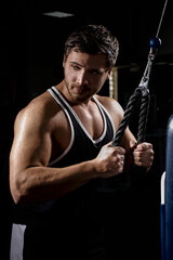 Muscular athletic young man fitness model do exercises in gym