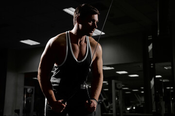 Muscular athletic young man fitness model do exercises in gym