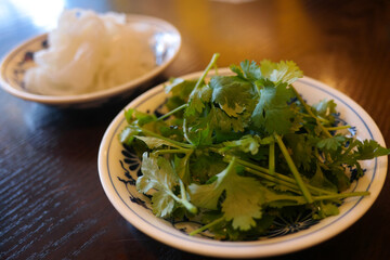 Coriander is on a white plate on the table.