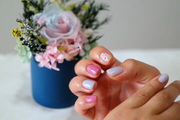 woman's hand in pink and white nail art.