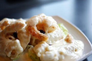 It's a fried shrimp with cream sauce on a white plate.