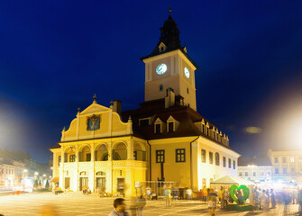 Fototapeta na wymiar Nightlife of Brasov main Council Square with illuminated Town Hall, Romania