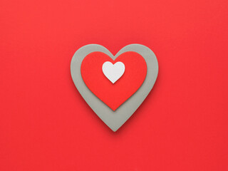 A set of three wooden hearts on a red background. The concept of falling in love and Valentine's...