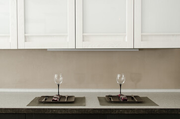 Prepared cutlery and glasses for two persons on the countertop in the kitchen