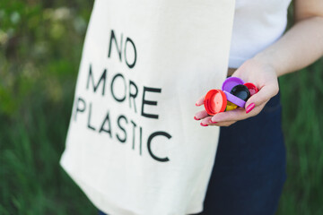 Woman hands are holding a handful of multi-colored plastic lids. Concept of environmental...