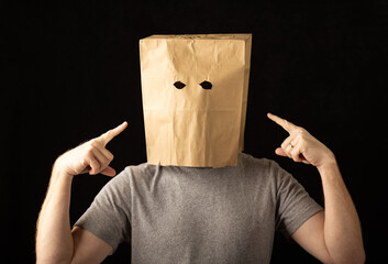 Man wearing a paper bag over his head and pointing at himself