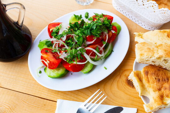 Delicious light vegetable salad made from sliced tomatoes, cucumbers, onion rings and parsley