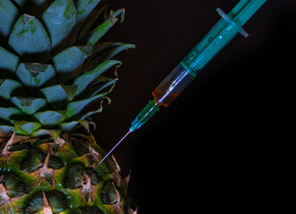 pineapple with an injected syringe - close up, black background