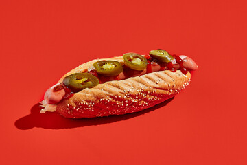 American hot dog with jalopeno on red background minimal style. Fast food on colour background with...