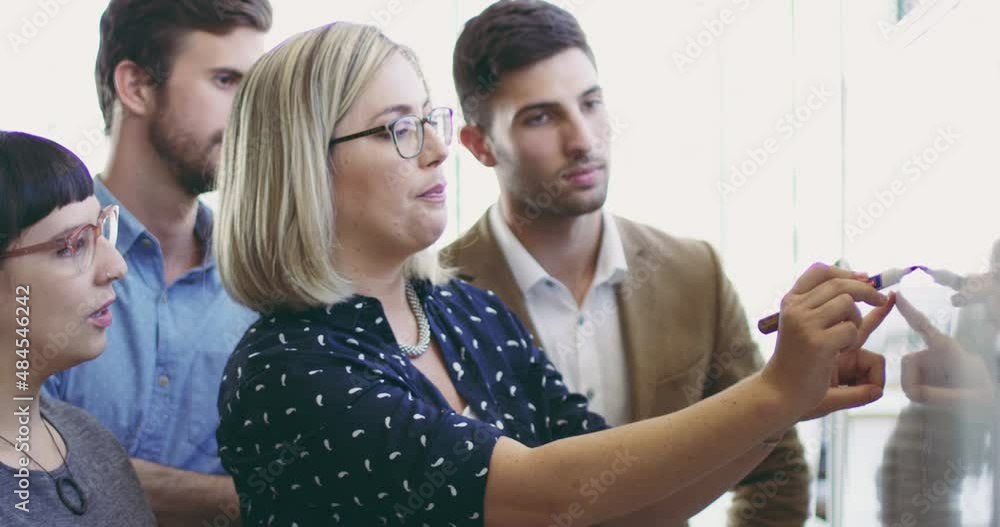 Wall mural Talking through their ideas as a team. Diverse businesspeople brainstorming and planning on a whiteboard in an office. Woman as manager writing and explaining notes, ideas and strategy in an agency