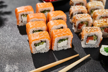 Maki sushi set on dark background. Maki set with variety rolls. Composition from popular sushi rolls and hosomaki. Style concept sushi menu with black background, leaves and hard shadow.