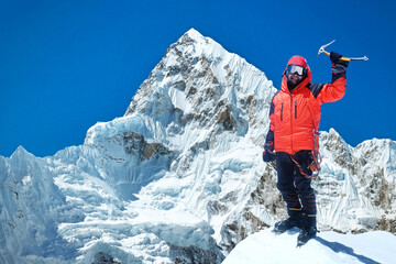 Alpinist standing on a summit, enjoying successful ascending. Mountain peak Everest on a background. Highest mountain in the world. National Park, Nepal.