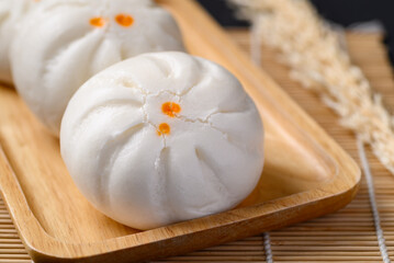 Obraz na płótnie Canvas Steamed Chinese bun stuffed with minced pork, egg yolk or sweet on wooden plate, Asian food
