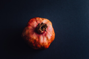 Dried red garnet on a dark background, rough texture of the peel of the fruit. space for text
