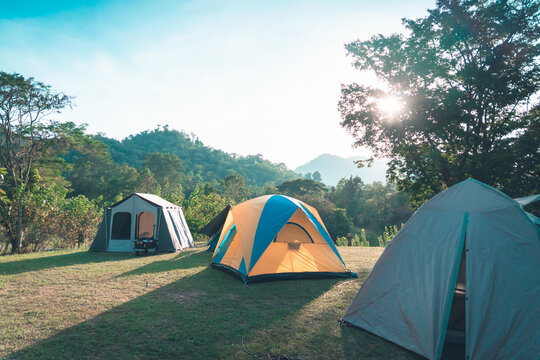 Camping site with three tents and Mountain Forest in the background.