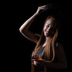 girl, in a hat, with a glass of cognac on a black background