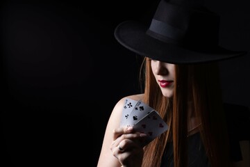 a girl in a hat with playing cards three sevens on a black isolate