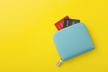 Blue wallet with credit card on yellow background - obrazy, fototapety, plakaty